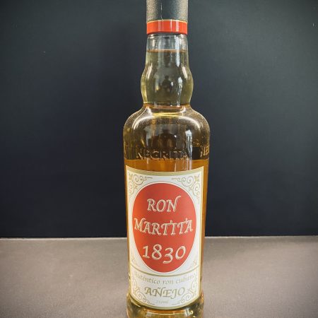 Botella de cristal de ron etiqueta roja encima de una mesa marron