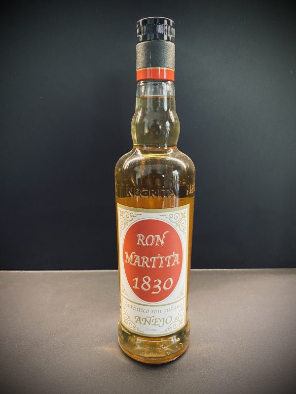 Botella de cristal de ron etiqueta roja encima de una mesa marron